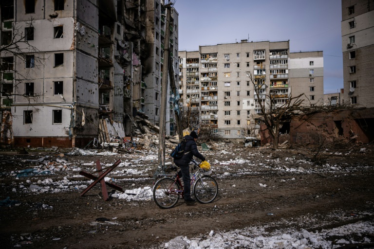 A man rides his bicycle on March 4, 2022 in front of residential buildings damaged in shelling in the city of Chernihiv, Ukraine