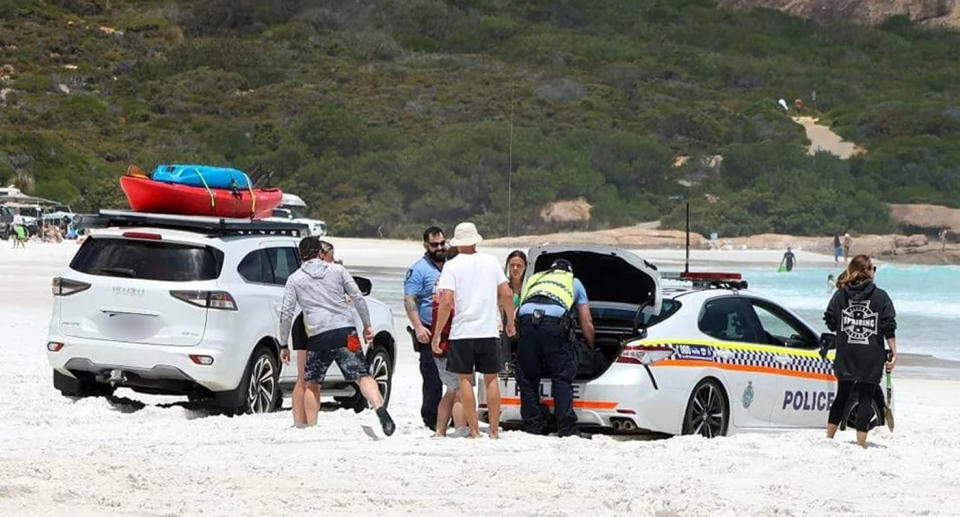 Locals on the beach rushed to the aid of the police officers after car got bogged on sand. 