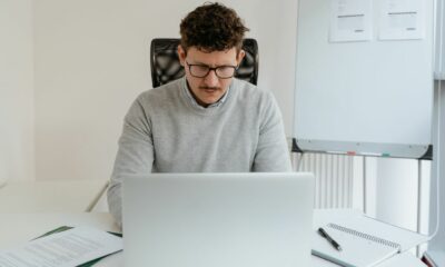 Photo of a man in a sweater working on his laptop