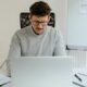 Photo of a man in a sweater working on his laptop