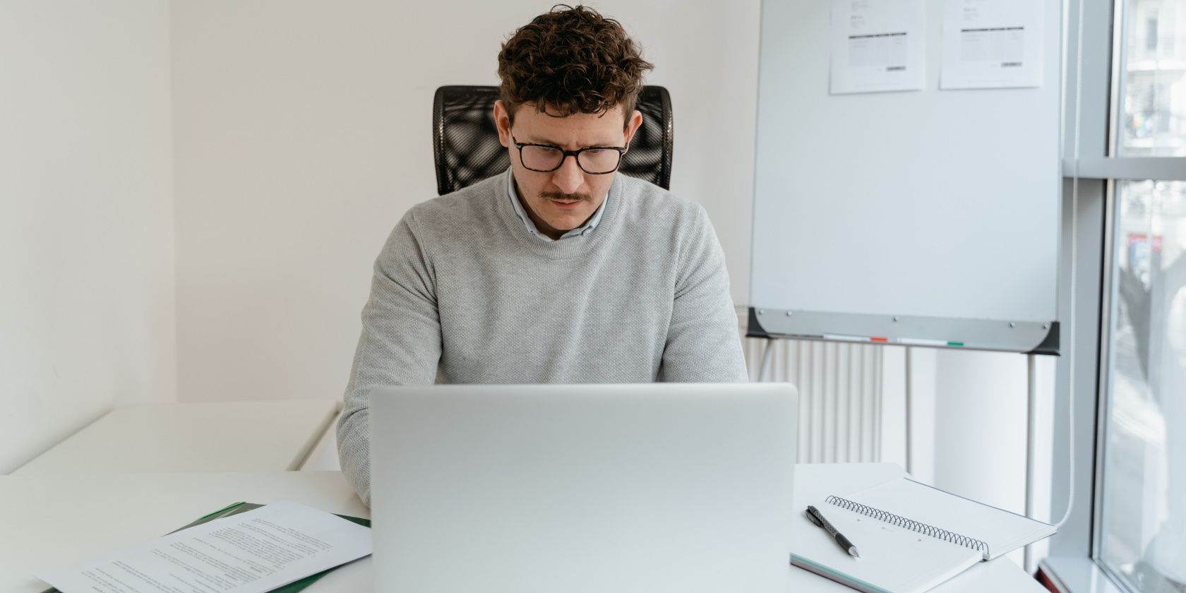 Photo of a man in a sweater working on his laptop