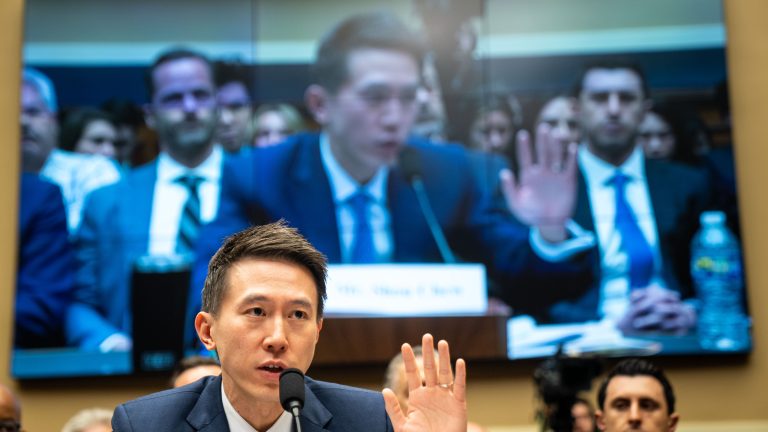 TikTok CEO Shou Zi Chew faces congress, his image projected on a TV screen behind him