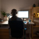 Rear view of an unrecognizable young woman working late on her computer from her home office.