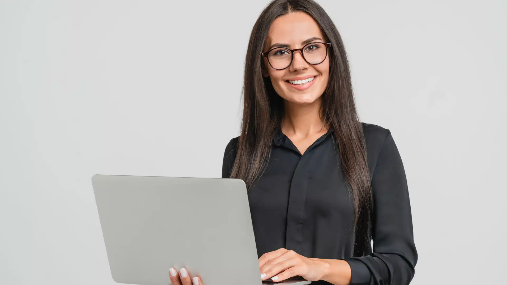 smiling woman wearing glasses and holding a laptop