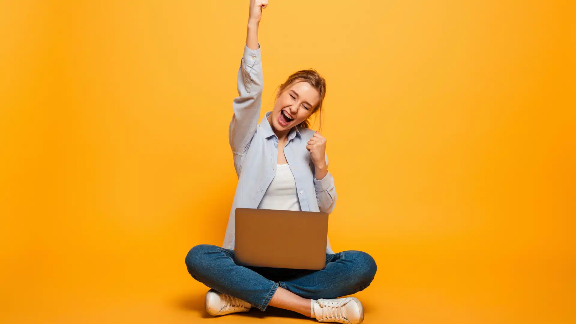 happy woman sitting crosslegged with computer in her lap