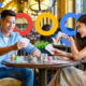 Couple Playing Cards At A Table In A Busy Restaurant Google Logo