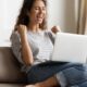 Woman sit on sofa put pc on lap clenched fists scream with joy while read great news on laptop. Gambler celebrate online auction bet victory. Got incredible offer sincere emotions of happiness concept