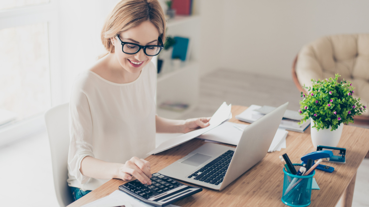 Happy cute pretty accountant working with computer and calculator.