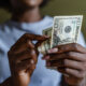 African American woman holding and counting dollars.