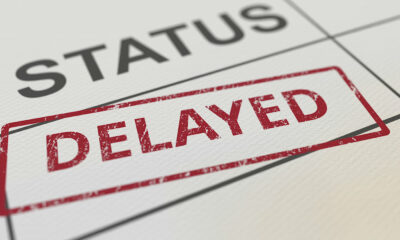 Close-up of a document with a grid and a red stamp that reads "delayed" over the word "status" due to Chrome's deprecation of third-party cookies.