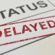 Close-up of a document with a grid and a red stamp that reads "delayed" over the word "status" due to Chrome's deprecation of third-party cookies.