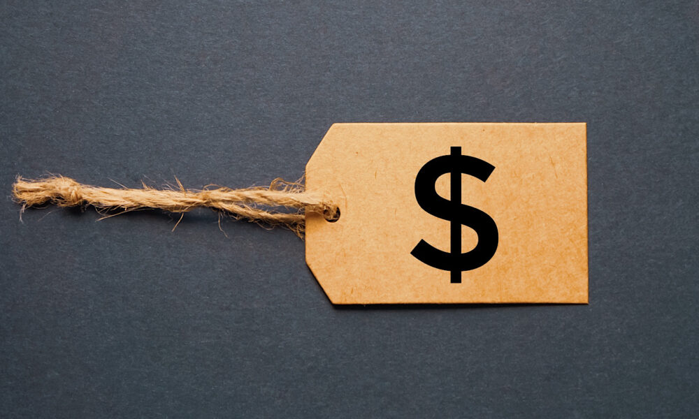 A brown cardboard price tag with a twine string and a black dollar sign symbol, influenced by the Link Tax Law, set against a dark gray background.