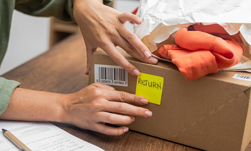 woman online shopper affixes a barcode sticker to a cardboard box, marking it for return and refund